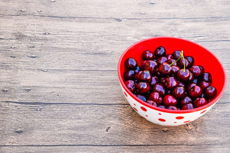 Berries of a sweet cherry on a wooden background in a plastic cup. Ripe red sweet cherry.の写真素材