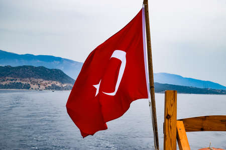 The flag of Turkey flutters in the wind on the deck of a pleasure yacht.の写真素材