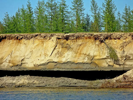 Crumbled cliff on the river bank. Clayey shore.の写真素材