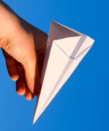 White paper airplane in hand against the sky. A symbol of freedom on the Internet.の写真素材