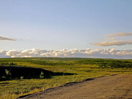 A dirt road in the tundra in the summer. The road from the rubble mound