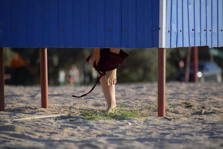 Dressing room on the beach, girl's legs are visible from the dressing room, the girl changes clothes on the beachの写真素材