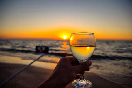 Selfie with a selfie stick on the beach at sunset with a glass of champagneの写真素材