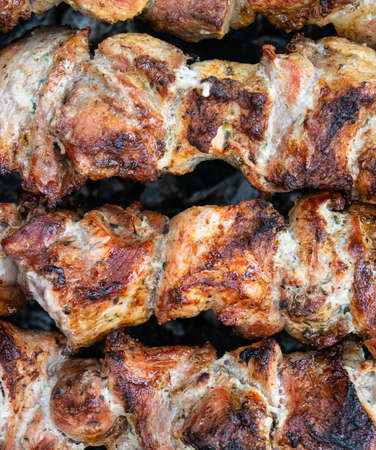Frying pork on a skewer over a brazier. Turning meat over coals. Appetizing shish kebab. Delicious barbecue.の写真素材