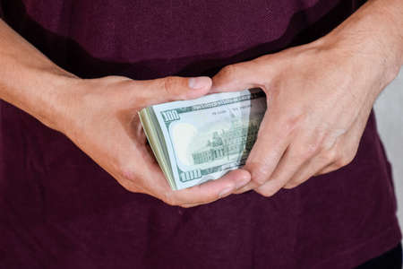 A man holds a wad of dollars in his hands. US Dollarsの写真素材
