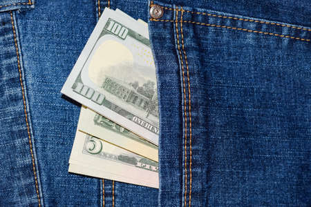 Dollars stick out of the pocket of jeans. money in your pocket.