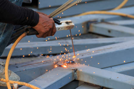 Asian worker making sparks while welding steel