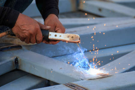 Asian worker making sparks while welding steel