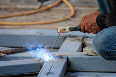 Asian worker making sparks while welding steel
