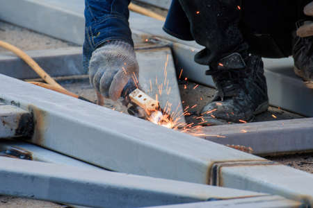 Asian worker making sparks while welding steel