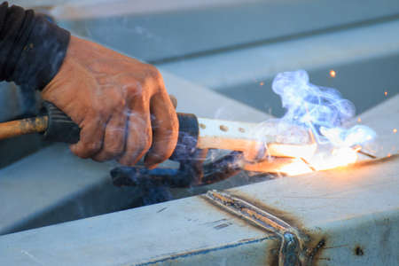 Asian worker making sparks while welding steelの写真素材
