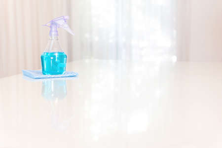 Spray bottle with light blue liquid on a white table with copy space.の写真素材