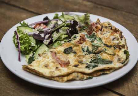 Omelette with mashrooms, bacon and vegetables served with saladの写真素材
