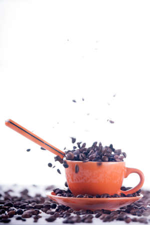 Cup of coffee on orange background with white beansの写真素材