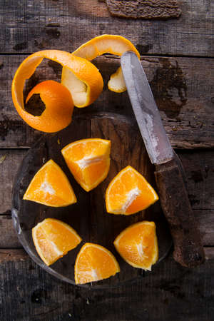 Peel an orange with the use of an old knife on the tableの写真素材