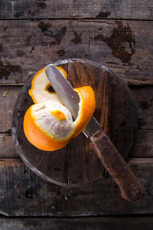 Peel an orange with the use of an old knife on the tableの写真素材