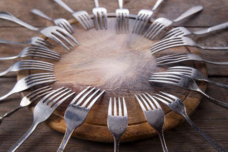 Sets of forks different shapes arranged on chopping roundの写真素材