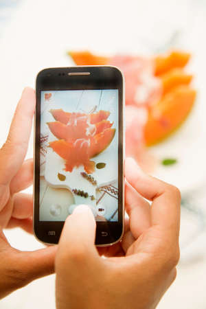 Taking pictures with the phone a plate of melon and hamの写真素材