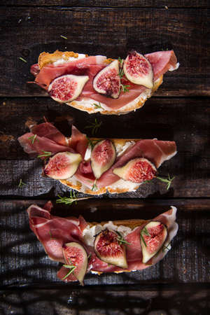 Presentation on wooden table bruschetta with figs and prosciuttoの写真素材