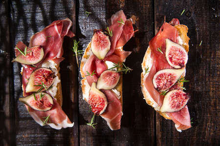 Presentation on wooden table bruschetta with figs and prosciuttoの写真素材