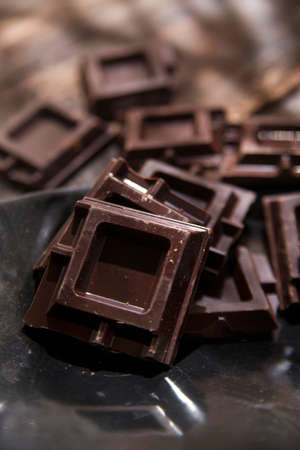 Presentation of some cubes of dark chocolate on wooden tableの写真素材