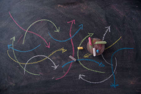 Curved colored arrows drawn with chalk on blackboardの写真素材