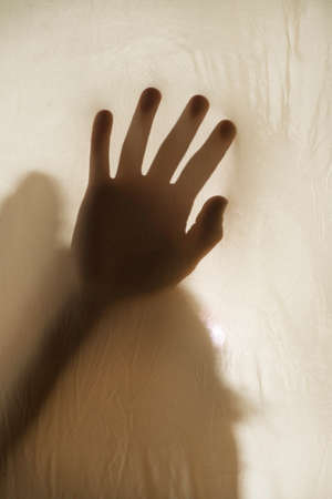 Photographic representation of violence on women, hands against sheetの写真素材