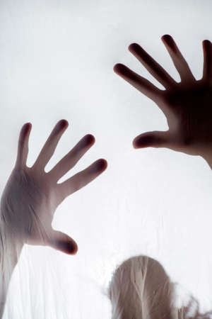Photographic representation of violence on women, hands against sheetの写真素材