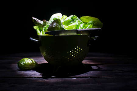 Presentation of a salad basket in a colander or on a black backgroundの写真素材