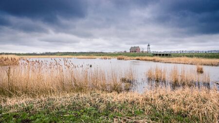 Old Port of the former Zuiderzee island; \"Schokland\" in the polder in the Netherlands. This world heritage of UNESCO shows a reconstruction of the breakwaters, piers, docks, lighthouse keepers house and light show. A residential mound amidst an agricultの写真素材
