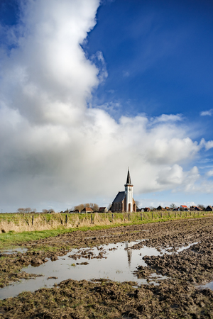 Panoramic shot of old Dutch church. Farmland. Stormy cloudy sky. Texel. Den Hoorn. Wadden island. The Netherlandの写真素材