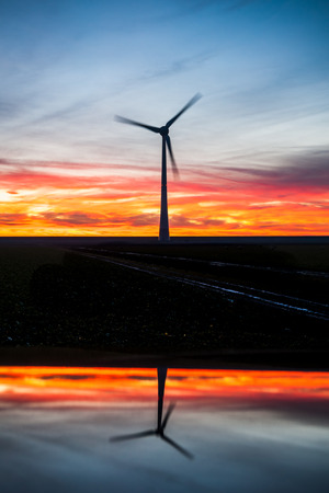 Silhouette of modern windmills for wind energy generation in the dutch polder. Picture taken at sunset in noordoostpolderの写真素材