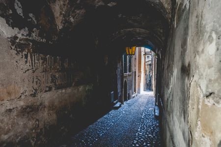 Covered arch passage in an old french medieval mountain village. An urban look with a beautiful old streetlight and arcades in a narrow alleyの写真素材