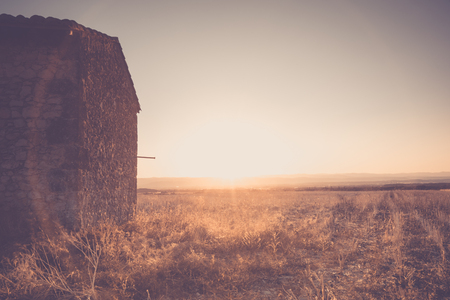 Romantic sunset above and french farmland with stubble of sunflowers and an old farmhouse in the middle of the landscape.の写真素材