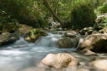Photo from mountain river that runs usually in mountains, in narrow, deep valley with steep banks, rocky stream bed, and accumulated rock debris. Mountain rivers are characterized by high slope and flow velocity, insignificant depth, frequent rapids and wの写真素材