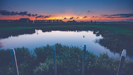 An old harbor head in the dry fallen polder of the Netherlands during sunset and the evening. A foot with contrasting and beautiful lightの写真素材