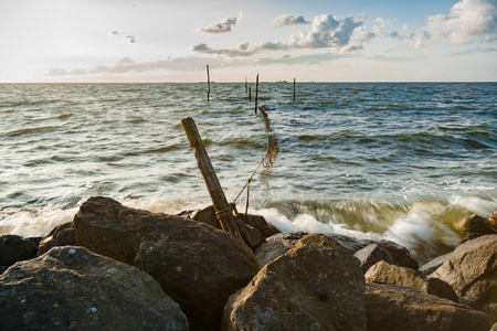 A lake at sunset with traditional fishing gear and waves that hit the coastの写真素材