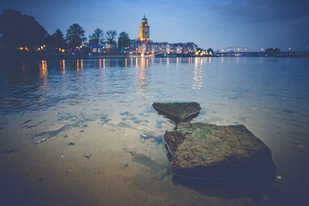 Deventer at night with view over the river Ijssel from a beach. The tower church is towered above the beautifully-featured cityscape.の写真素材