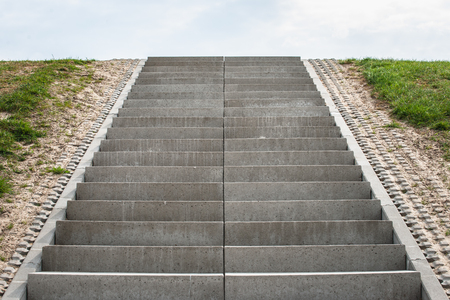 Stairway to heaven. Cultivated landscape with upward climbing stair stairs. Sea dike with green...