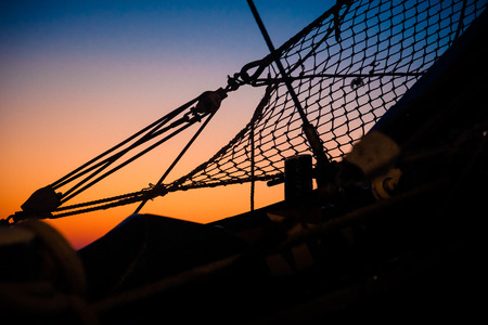 Ropes, nets, cables, pulleys and bollards as shadows against a colorful sky of red and blue colors of the sunset.の写真素材