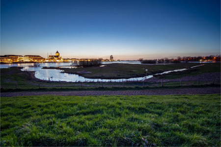 Nightfall with blue sky and long exposure above the old medieval city of Kampen in the Netherlands with its beautiful skylineの写真素材