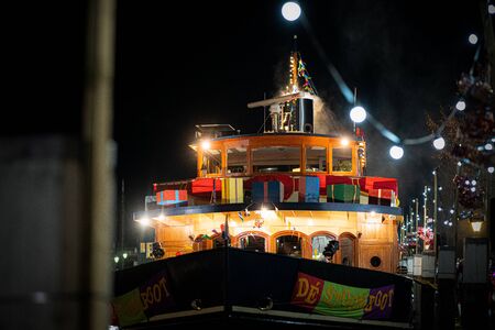 Classic steam ship with wooden paneling on the quay of a harbor with the festive decoration
