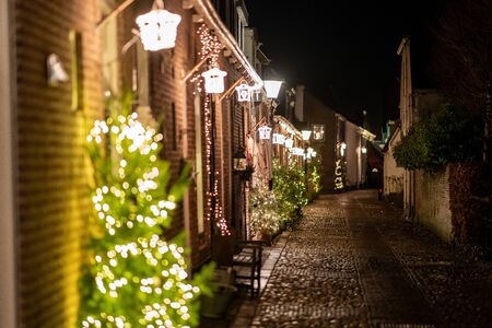 Old narrow street in a small town with atmospheric Christmas lightsの写真素材