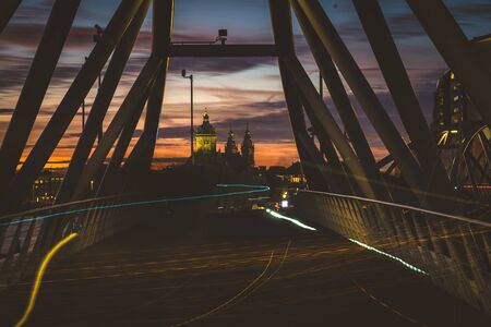 Twilight traffic bridge with long exposure lamps with and the Amsterdam church in the backgroundの写真素材