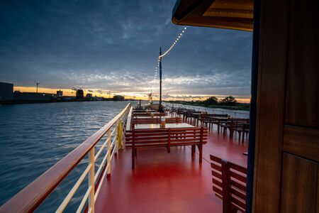 View over a river in the dutch delta, cloudy sky with sunset from the top deck of a tall shipの写真素材