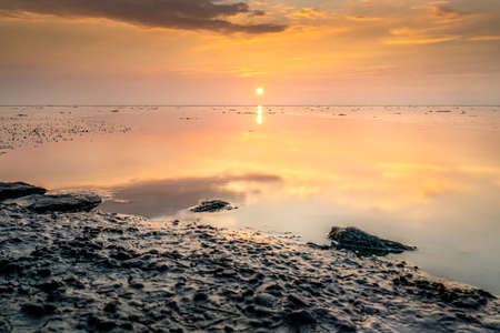 Tranquil and tranquil zen-like sunset on the beach with beautiful colors in pink and red with...