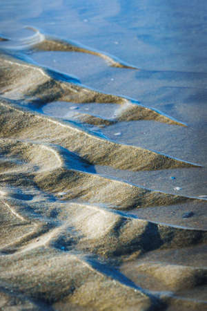 Close up of water and sand patterns on sandy beach of dutch north sea coast