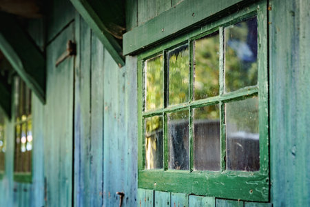 Side view of wooden planks with characteristic green painted window with typical small authentic...