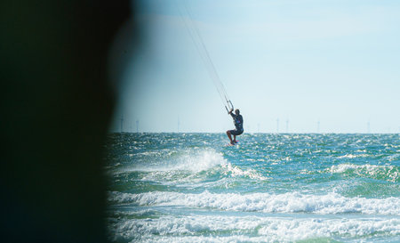 People enjoy riding kite surf board in sun uv protection suit on bright sunny day at sea or ocean...