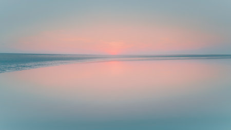 Serene image capturing the ethereal beauty of a calm body of water meeting the horizon at twilight.の写真素材